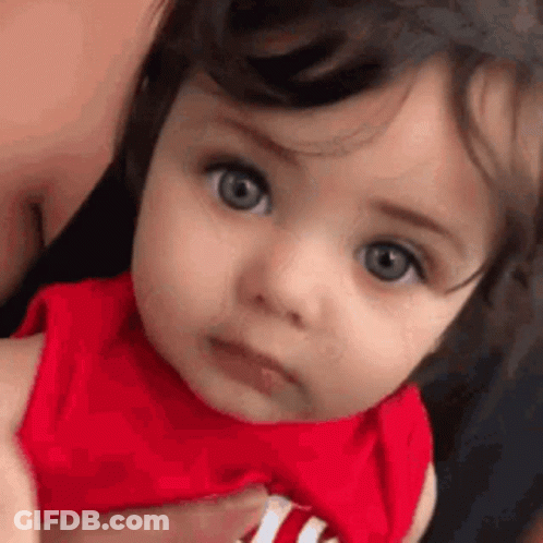 Close Up Of Baby In Red Shirt Looking At Camera GIF