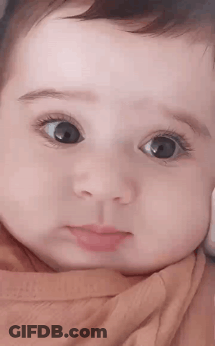 Close Up Of Baby With Big Eyes And Pink Shirt GIF