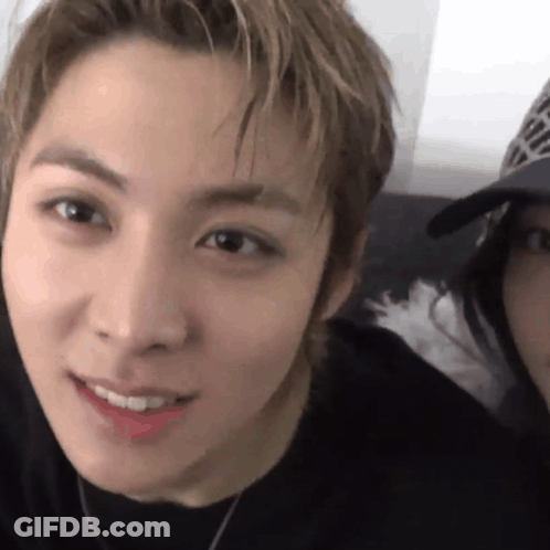Close Up Of Man With Woman In Baseball Cap Behind Him GIF