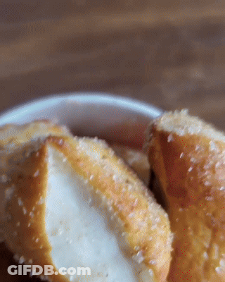 Close Up Of Two Pretzels In Bowl With Sauce GIF