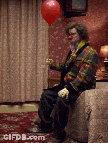 Clown Sitting On Bed With Red Balloon GIF