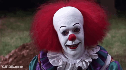Clown With Red Hair And Red Nose Standing In Grass GIF