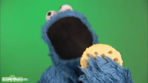 Cookie Monster From Sesame Street Eating A Cookie On A Green Background GIF