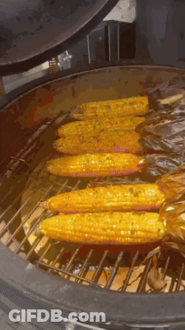 Corn On The Cob Is Being Cooked On A Grill With The Lid Open GIF