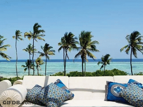 Couch With Blue Pillows On Balcony Overlooking Ocean GIF