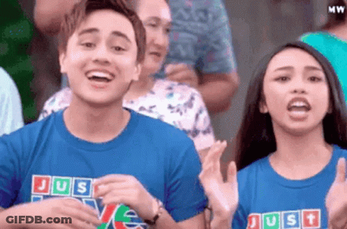 Couple Clapping In Crowd With Blue Shirts Saying Just Love GIF