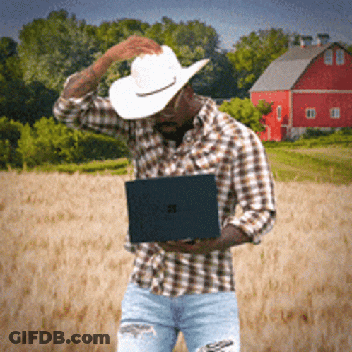 Cowboy Hat Man Holding Laptop In Front Of Red Barn GIF