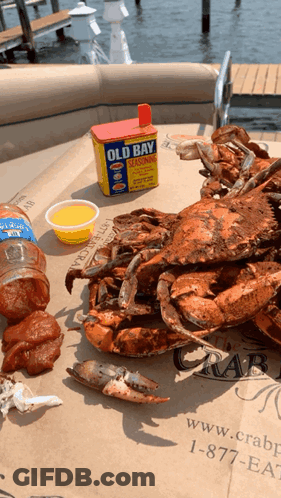 Crabs And A Can Of Old Bay Seasoning On A Table GIF