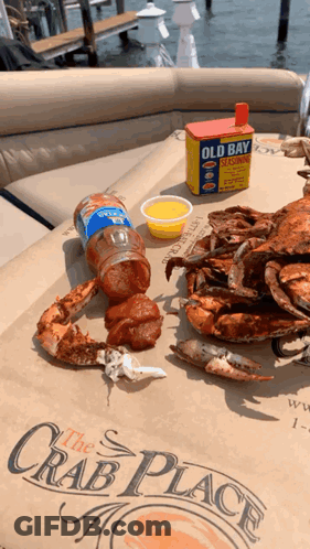 Crabs Are Sitting On A Table With A Box Of Old Bay Seasoning In The Background GIF
