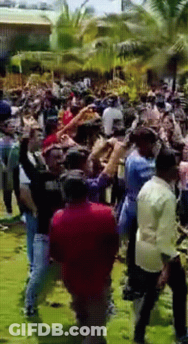 Crowd Gathered In Grassy Area With Man In Red Shirt GIF