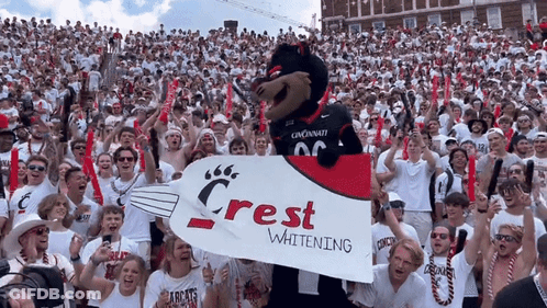 Crowd Holding Crest Whitening Banner GIF