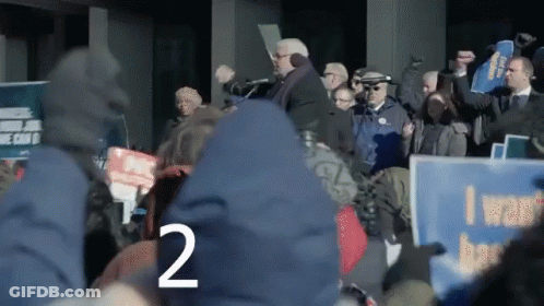 Crowd Holding Signs Including I Want Better GIF