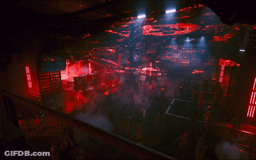 Crowd In Dark Room With Red Ceiling Lights GIF