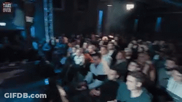 Crowd In Dark Room With Take Over Sign GIF