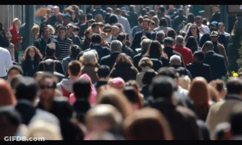 Crowd Walking Down Street With Sign GIF