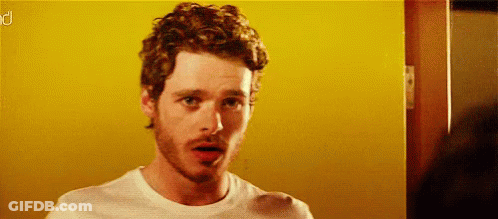 Curly Bearded Man In White Shirt Before Yellow Wall GIF