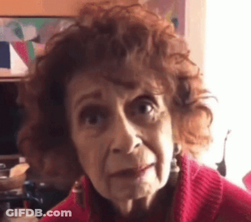 Curly Haired Elderly Woman In Red Sweater Making Funny Face GIF