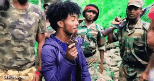 Curly Haired Man Holding Gun In Front Of Soldiers GIF