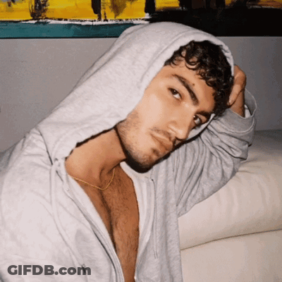 Curly Haired Man In Grey Hoodie Looking At Camera GIF
