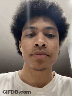 Curly Haired Man In White Shirt Looking At Camera GIF