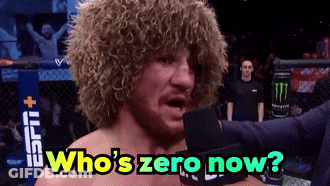 Curly Haired Man Into Mic Saying Who's Zero Now GIF