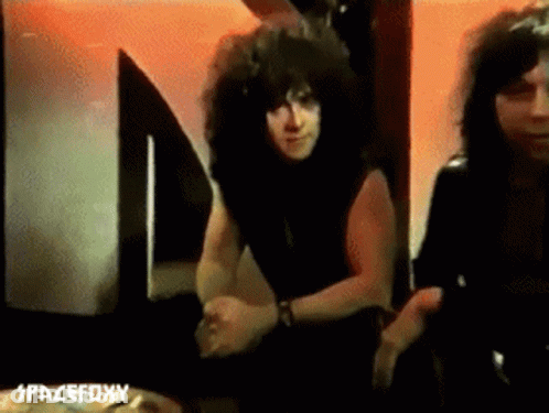Curly Haired Man Next To Another Man At Spacefoxy Sign GIF
