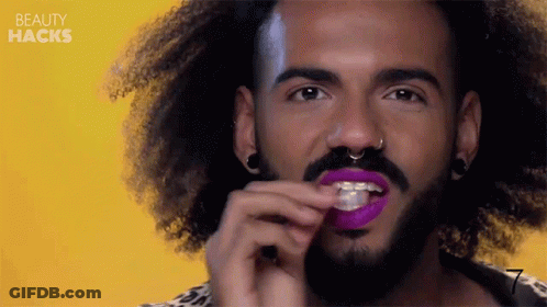 Curly Haired Man With Beard Applying Purple Lipstick GIF