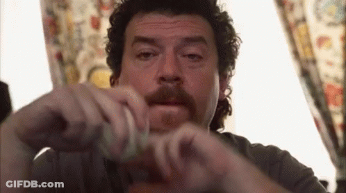 Curly Haired Man With Mustache Holding Condom By Window GIF