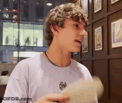Curly Haired Young Man Holding Paper By Picture Wall GIF