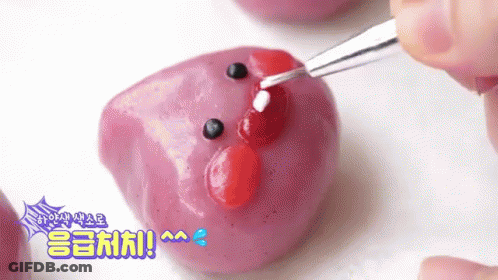 Decorating Purple Marshmallow With Red And White Icing And Fork GIF