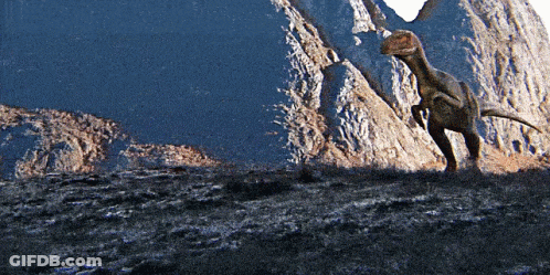 Dinosaur Standing In Front Of Rocky Cliff GIF
