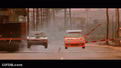 Dodge Charger And Red Sports Car Racing Down City Street GIF
