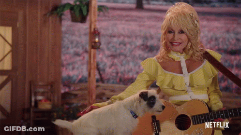 Dolly Parton Is Holding A Guitar Next To A Small Dog GIF