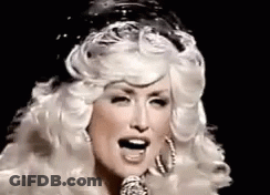 Dolly Parton Singing Into Microphone With Wig And Earrings GIF