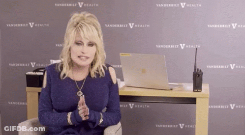 Dolly Parton Sitting In Front Of Vanderbilt Health Sign GIF