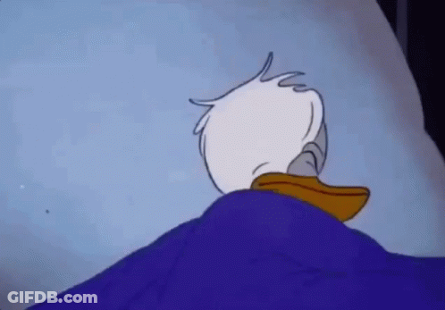Donald Duck Is Laying In A Bed With A Blue Blanket On Top Of Him . GIF