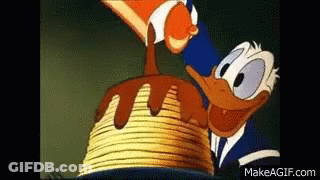 Donald Duck Is Standing Next To A Stack Of Pancakes With Chocolate Sauce Being Poured On Them . GIF