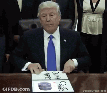 Donald Trump Sitting At Table With DonaldDraws.com Sign GIF