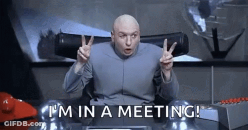 Dr. Evil Giving Peace Sign At Desk Meeting GIF
