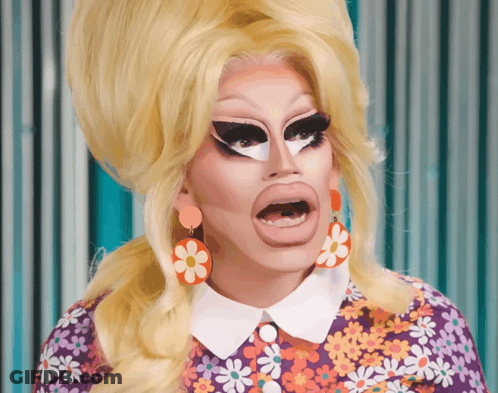 Drag Queen In Purple Shirt With Daisies And Earrings GIF