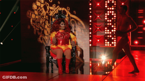 Drag Queen Sitting On Throne With Man Behind GIF
