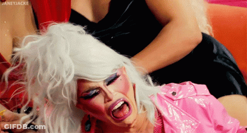 Drag Queen With White Hair And Pink Lipstick Held By Another Drag Queen GIF