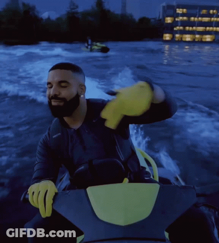 Drake Is Riding A Jet Ski In The Water With A Yellow Glove On GIF