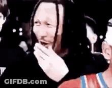 Dreadlocked Man Laughing Covering Mouth In Crowd GIF