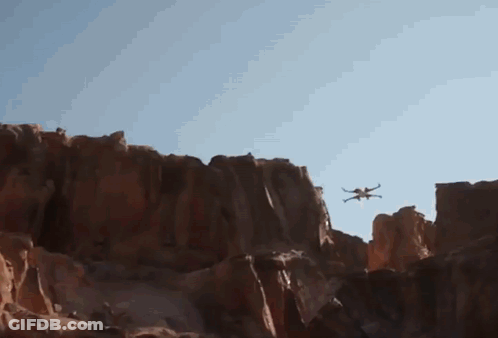 Drone Flying Over Rocky Cliff Blue Sky GIF