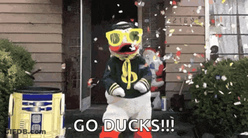 Duck Mascot Dancing In Front Of House With Confetti GIF