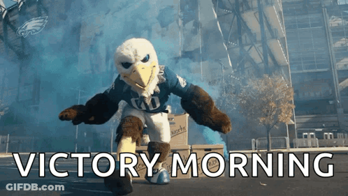 Eagle Mascot Says Victory Morning In Front Of Large Building GIF