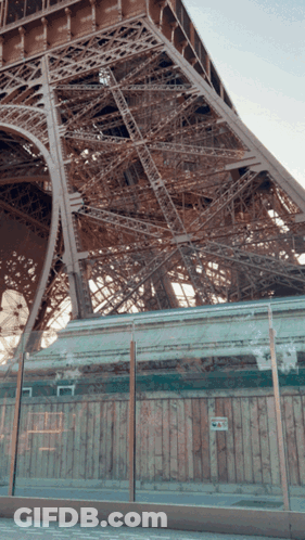 Eiffel Tower Behind Glass Fence And Wooden Wall GIF