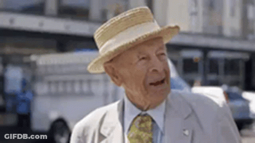 Elderly Man In Straw Hat And Tie Standing On Street GIF