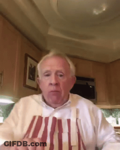 Elderly Man In Striped Apron And White Shirt Looking At Camera GIF